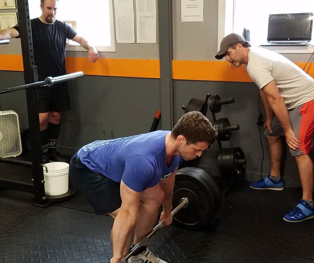 professional barbell coach teaching the Deadlift to client